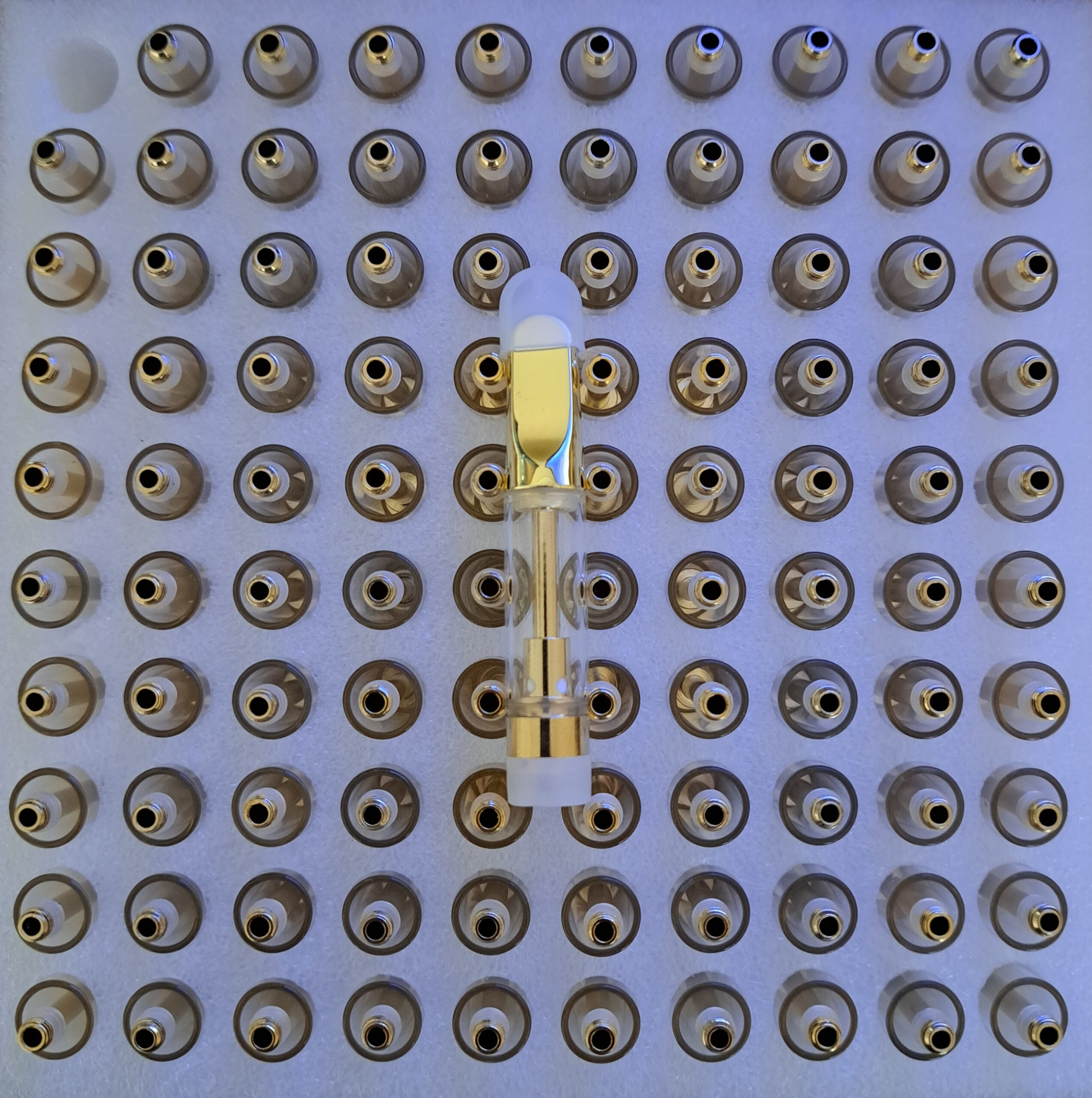 A display with a lot of small Gold - 1ml bottles on it.