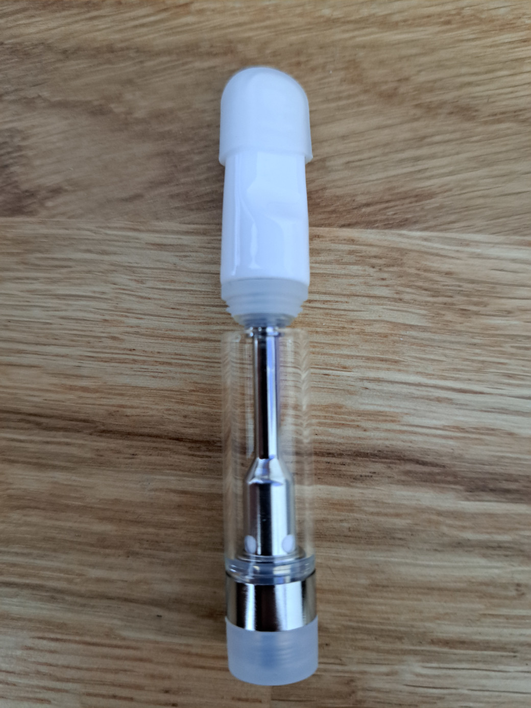 A small V4-SS - White Tip -1ml glass bottle sitting on top of a wooden table.