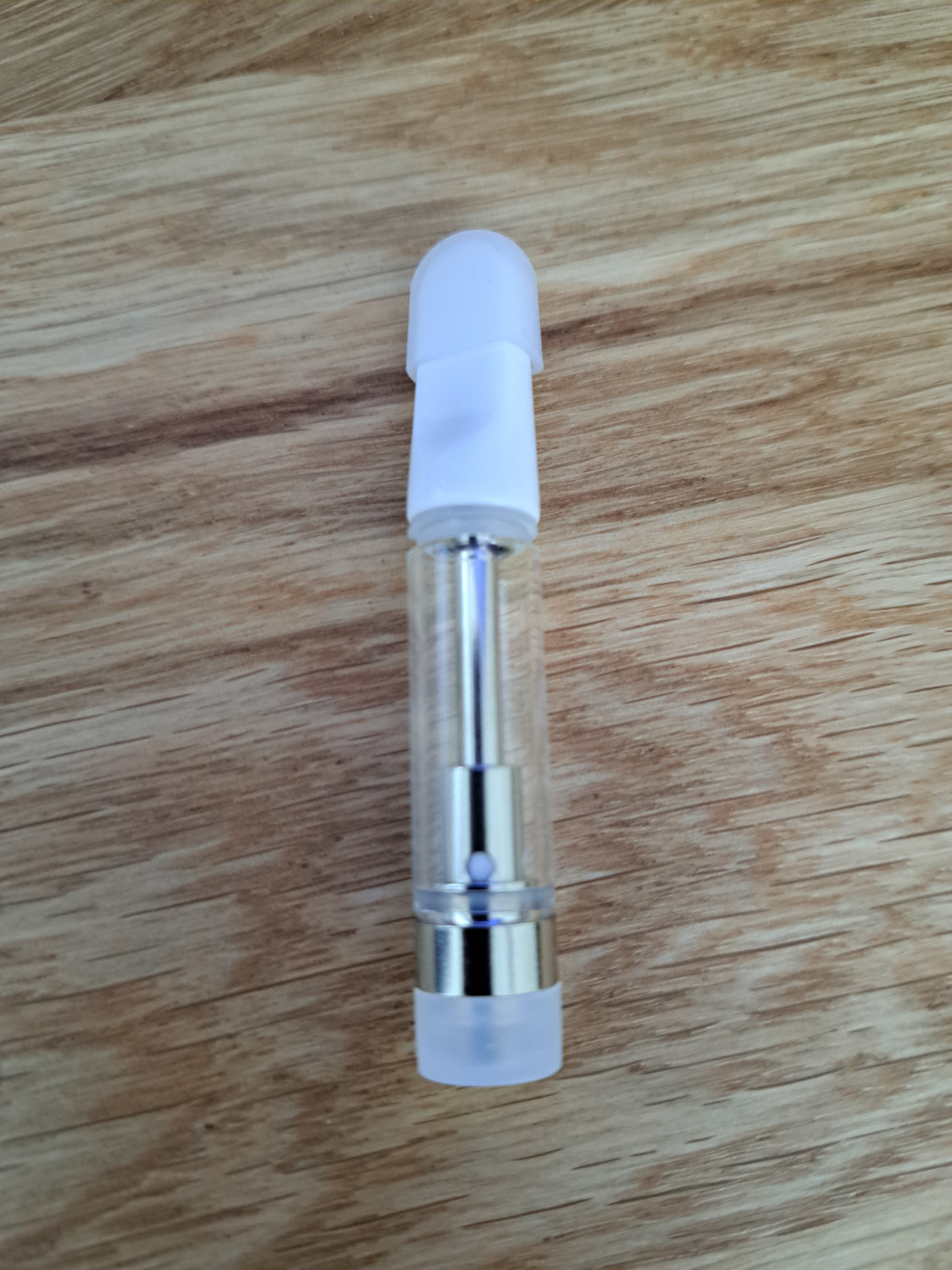 A V4 - White Tip - 1ml empty vape cartridge placed on a wooden table.